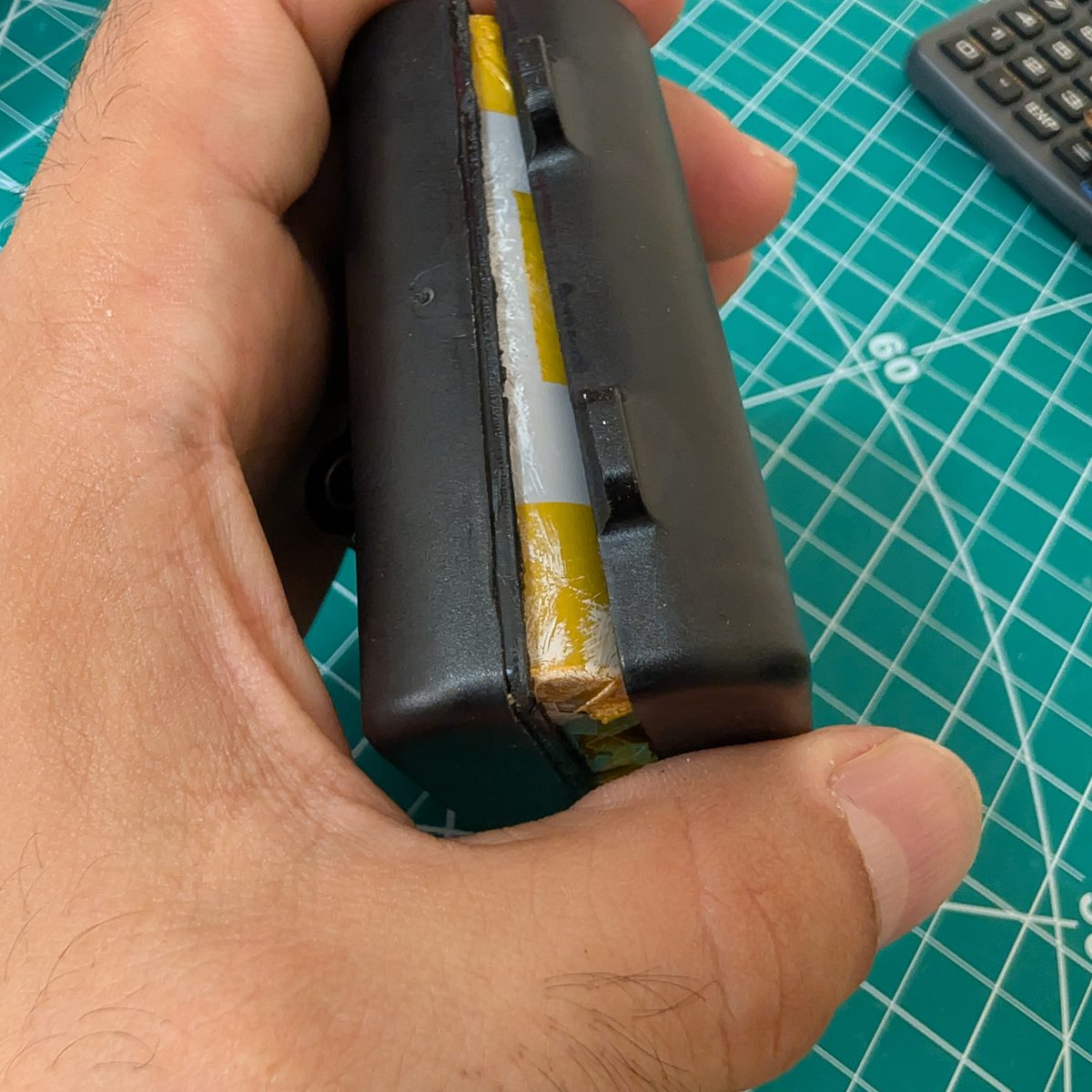 A NAO battery pack part-way open, the factory-bonded seam separated to reveal the cell string inside