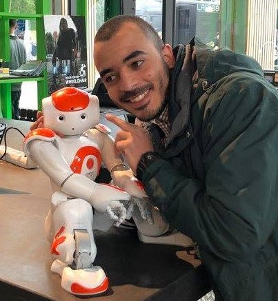Tarek smiling beside a NAO robot standing on a counter